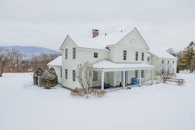 snow covered property with a mountain view and a porch