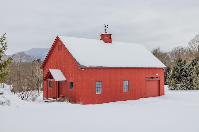 snow covered structure with a garage and a mountain view