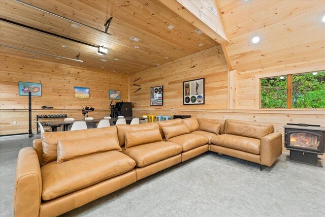 living room with wooden ceiling, wooden walls, and a wood stove