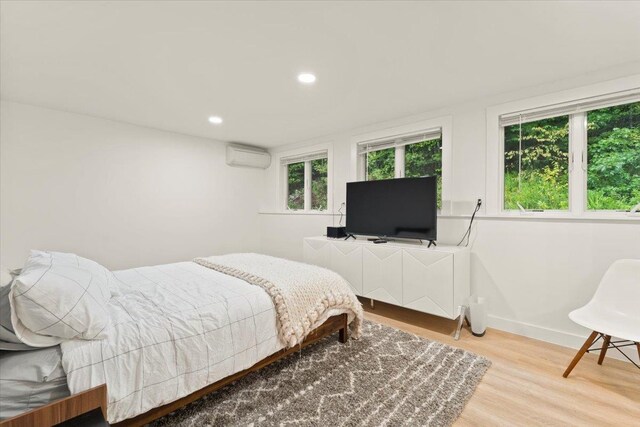 bedroom featuring light hardwood / wood-style floors and a wall unit AC