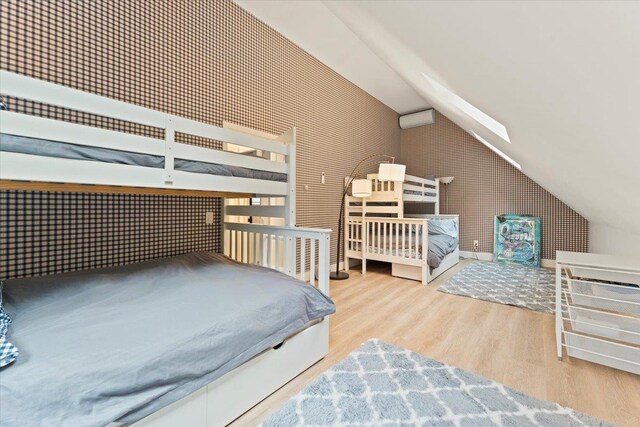 bedroom with vaulted ceiling and light hardwood / wood-style flooring