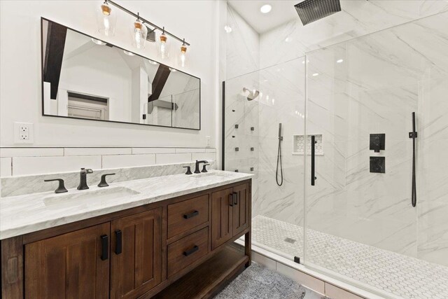 bathroom featuring dual vanity, backsplash, a shower with door, and tile walls