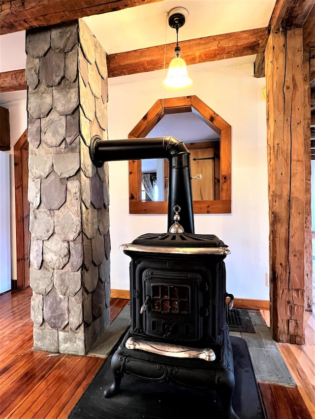 details featuring a wood stove, dark wood-type flooring, and beamed ceiling