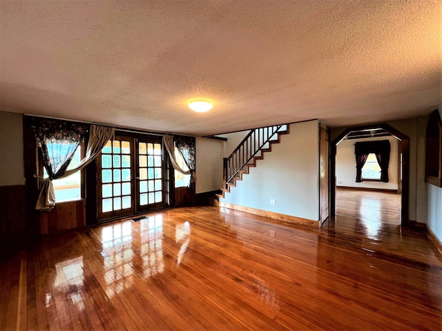 unfurnished room featuring a textured ceiling, dark wood-type flooring, and french doors