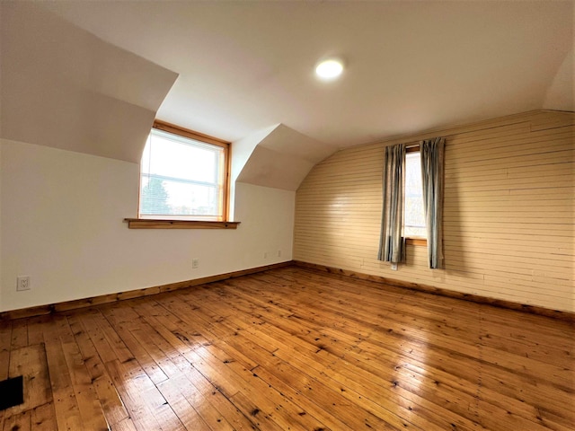 bonus room with light wood-type flooring, a healthy amount of sunlight, and lofted ceiling