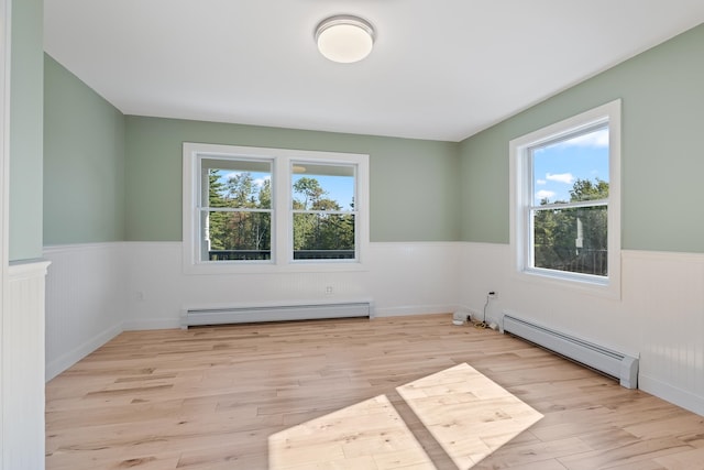 empty room featuring a baseboard radiator and light hardwood / wood-style flooring