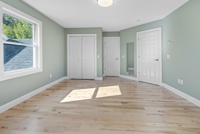 unfurnished bedroom featuring multiple closets and light hardwood / wood-style flooring