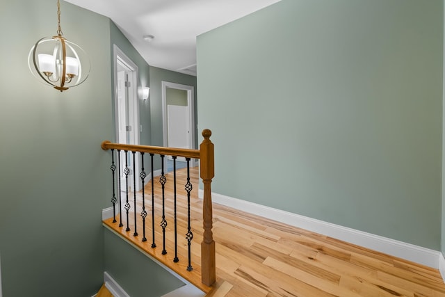 corridor featuring a notable chandelier and light hardwood / wood-style floors