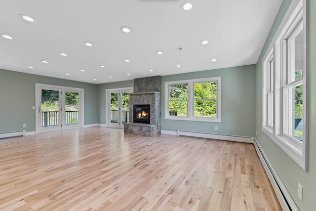 unfurnished living room featuring a baseboard heating unit, light wood-type flooring, and a fireplace