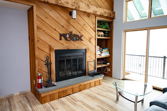 living room with a towering ceiling, hardwood / wood-style flooring, built in features, and wood walls