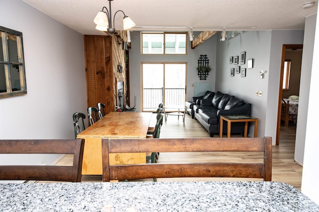 dining area with hardwood / wood-style floors, a textured ceiling, and an inviting chandelier