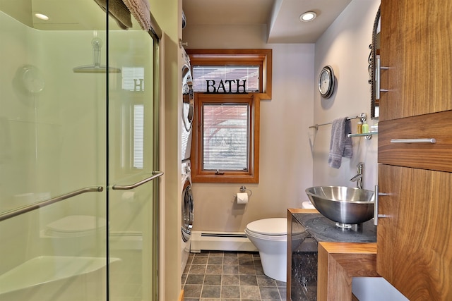 bathroom with toilet, baseboard heating, stacked washer / drying machine, vanity, and tile floors