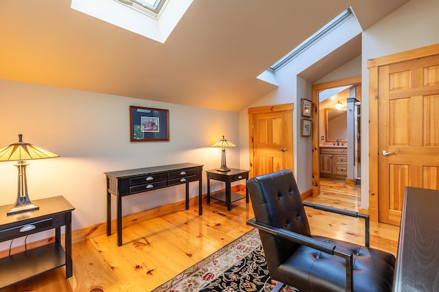 home office featuring vaulted ceiling with skylight and light wood-type flooring