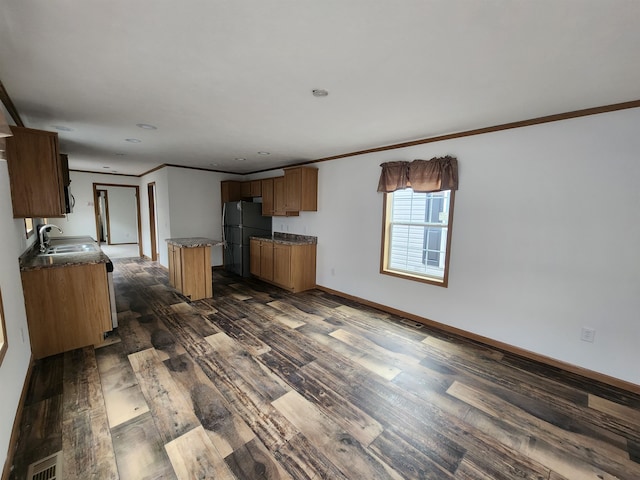 kitchen with ornamental molding, a kitchen island, dark hardwood / wood-style flooring, black refrigerator, and sink