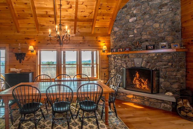 dining room with wood ceiling, vaulted ceiling with beams, hardwood / wood-style floors, a fireplace, and wood walls