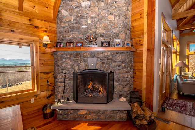 room details featuring a stone fireplace, hardwood / wood-style floors, and wooden walls