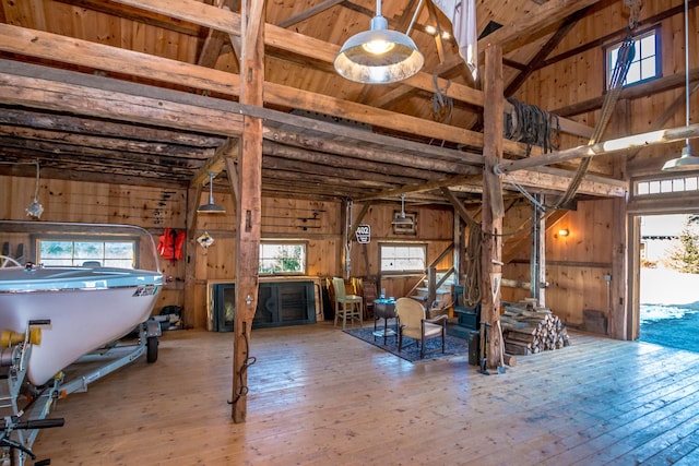 miscellaneous room with hardwood / wood-style flooring, vaulted ceiling with beams, a wealth of natural light, and wood walls