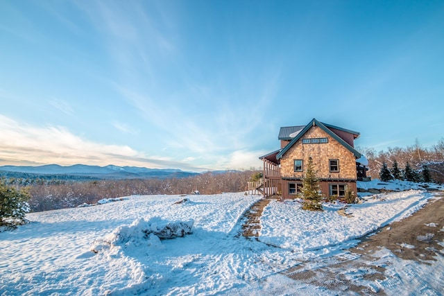 snow covered rear of property featuring a mountain view