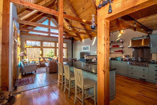 kitchen featuring stainless steel gas cooktop, a kitchen bar, light wood-type flooring, and beam ceiling