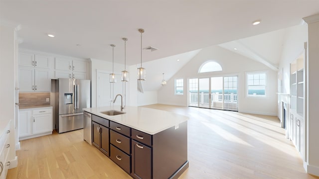 kitchen featuring white cabinetry, an island with sink, sink, hanging light fixtures, and stainless steel appliances