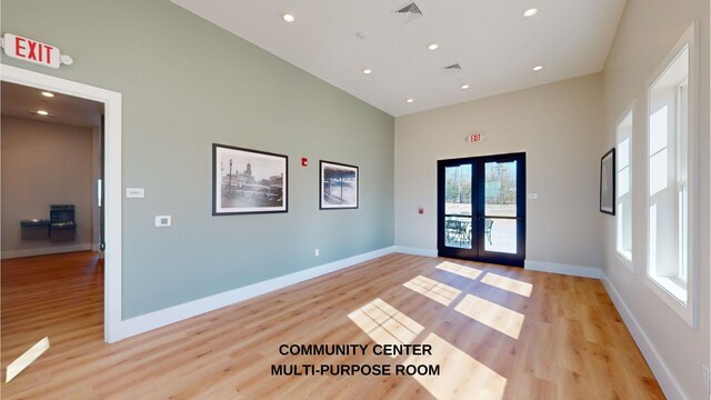 interior space with light hardwood / wood-style flooring, french doors, and a high ceiling