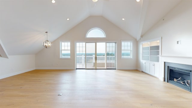 unfurnished living room featuring high vaulted ceiling, built in features, light hardwood / wood-style floors, and a chandelier