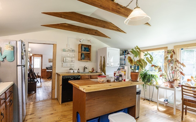 kitchen featuring pendant lighting, refrigerator, wood counters, black dishwasher, and stacked washer and clothes dryer