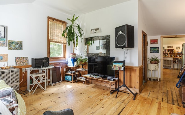 living room featuring vaulted ceiling, light wood-type flooring, and wood walls