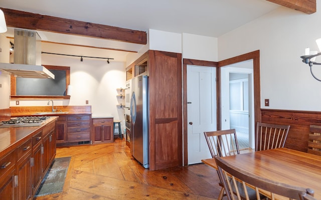 kitchen featuring sink, appliances with stainless steel finishes, light hardwood / wood-style floors, island exhaust hood, and wood walls