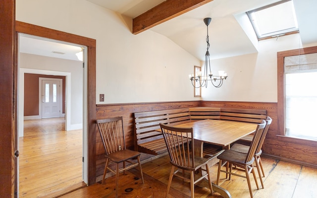 dining room featuring hardwood / wood-style floors, a chandelier, and vaulted ceiling with skylight