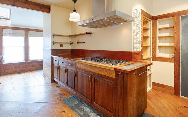 kitchen with wood counters, island range hood, decorative light fixtures, and stainless steel gas cooktop