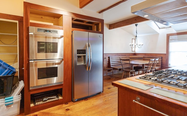 kitchen featuring light hardwood / wood-style flooring, stainless steel appliances, decorative light fixtures, exhaust hood, and beamed ceiling