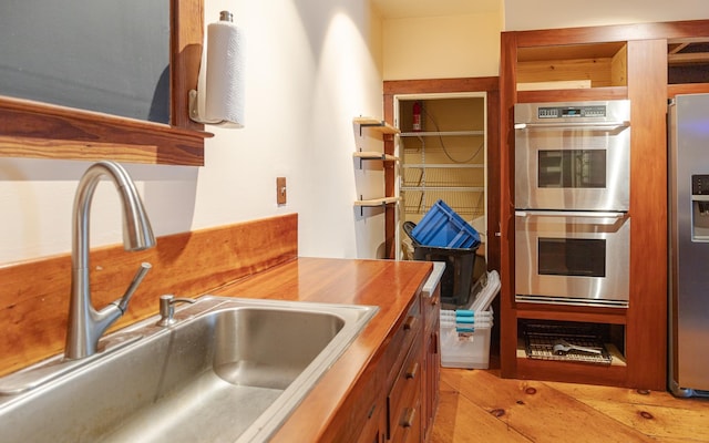 kitchen featuring stainless steel appliances, sink, and light wood-type flooring