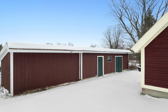 snow covered structure with an outbuilding