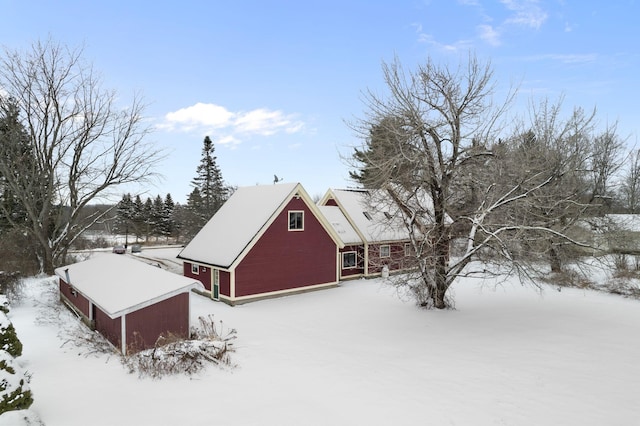 snow covered property with a garage and an outbuilding