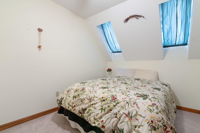 carpeted bedroom with lofted ceiling with skylight and baseboards