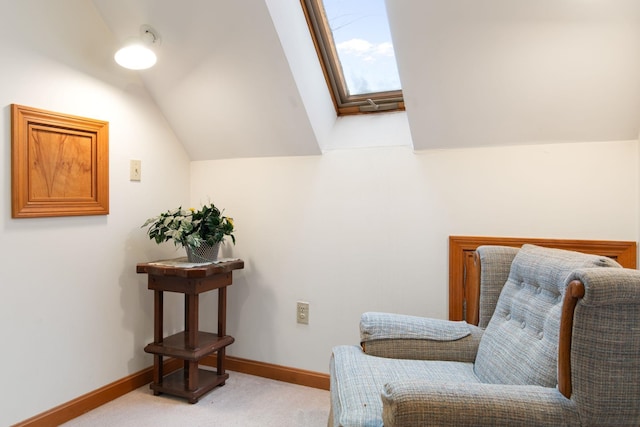 sitting room with carpet, vaulted ceiling with skylight, and baseboards