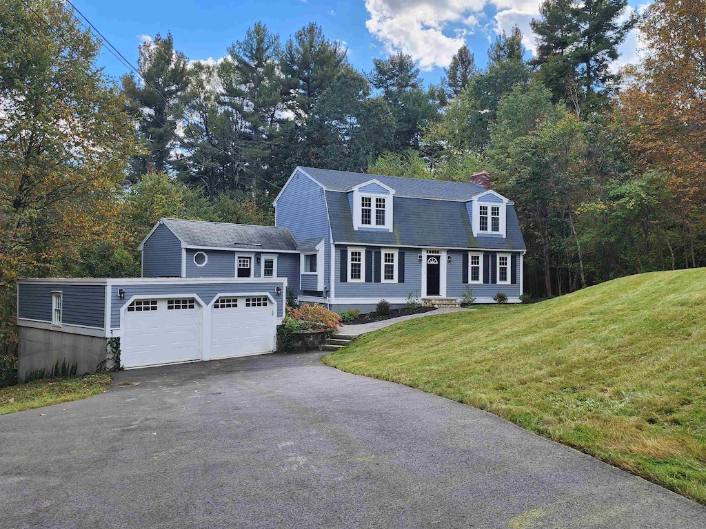 cape cod home with a front lawn and a garage