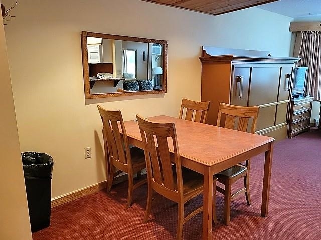 dining room with dark carpet and wood ceiling