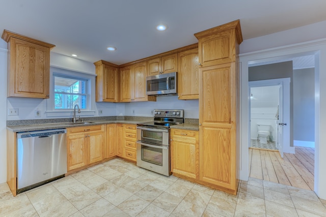 kitchen featuring dark stone countertops, sink, light tile flooring, and stainless steel appliances