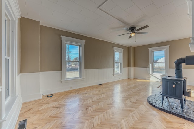 empty room featuring light parquet floors, a wood stove, and a wealth of natural light