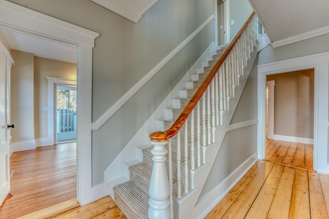 staircase with light hardwood / wood-style floors and crown molding