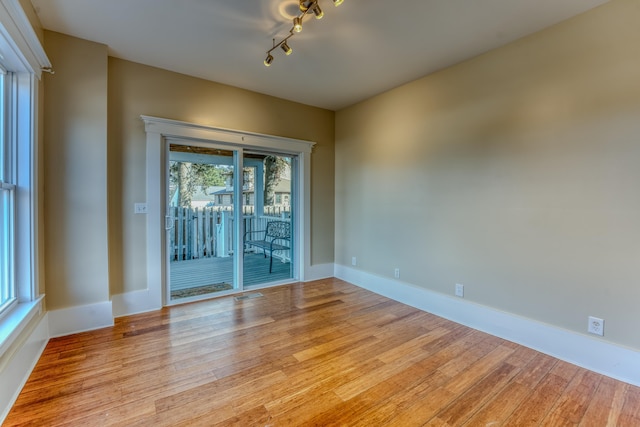 unfurnished room with track lighting and light hardwood / wood-style floors