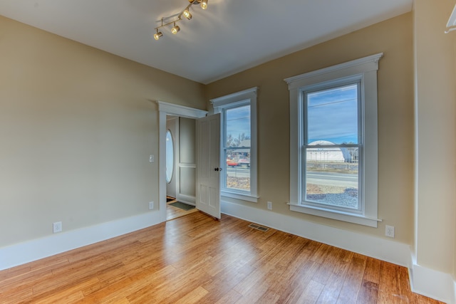 spare room with rail lighting and light hardwood / wood-style flooring