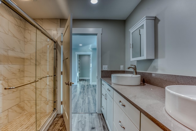 bathroom with double sink vanity, a shower with door, and hardwood / wood-style flooring