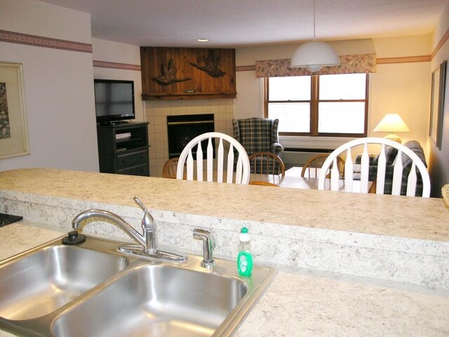 kitchen featuring decorative light fixtures, sink, and a fireplace