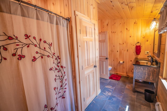 bathroom featuring toilet, wooden walls, vanity with extensive cabinet space, a baseboard heating unit, and tile flooring