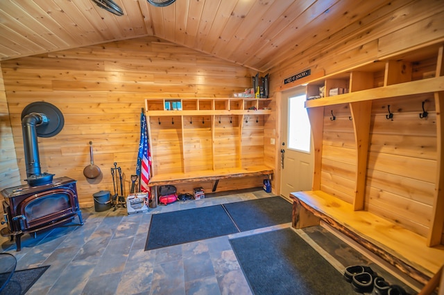 mudroom featuring wooden ceiling, dark tile flooring, a wood stove, wooden walls, and lofted ceiling