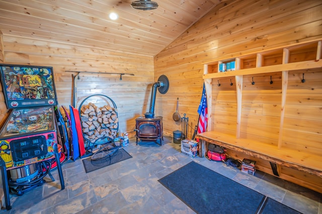 mudroom with wooden ceiling, wood walls, a wood stove, dark tile flooring, and vaulted ceiling