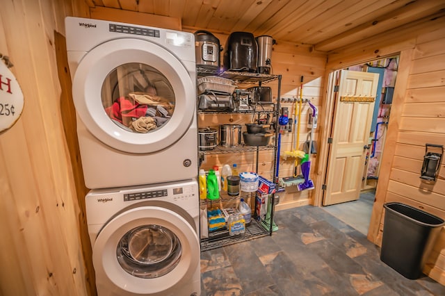 washroom featuring wood walls, wooden ceiling, stacked washer / drying machine, and dark tile floors